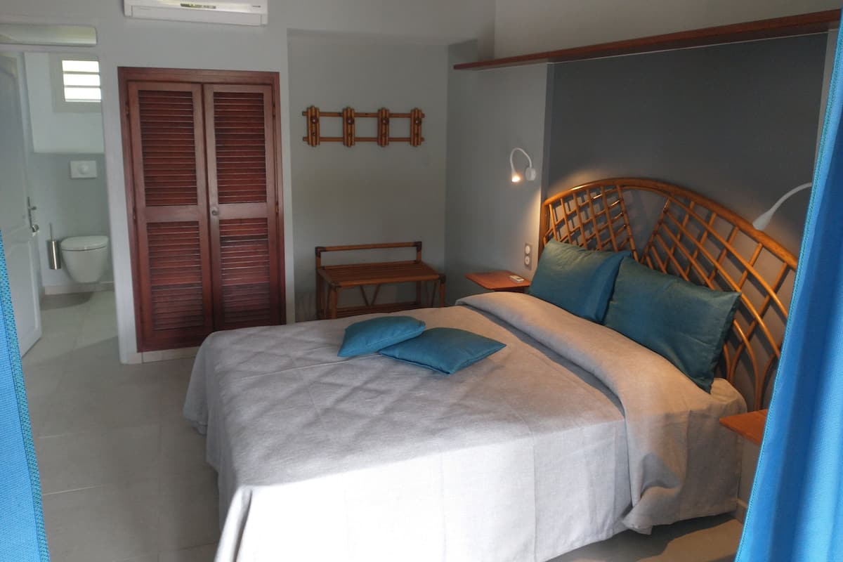 A bedroom with a bed, wooden headboard, bedside tables, and a wardrobe.