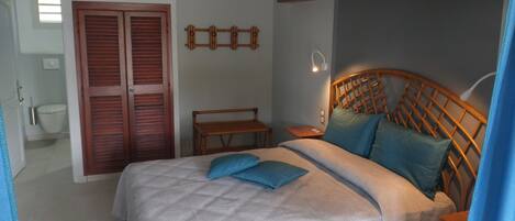 Een slaapkamer met een bed, een houten hoofdbord, nachtkastjes en een kledingkast.