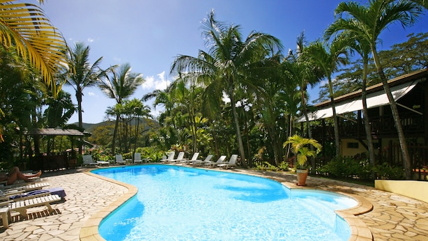 A swimming pool with lounge chairs and palm trees. - Habitation Grande Anse (Deshaies)