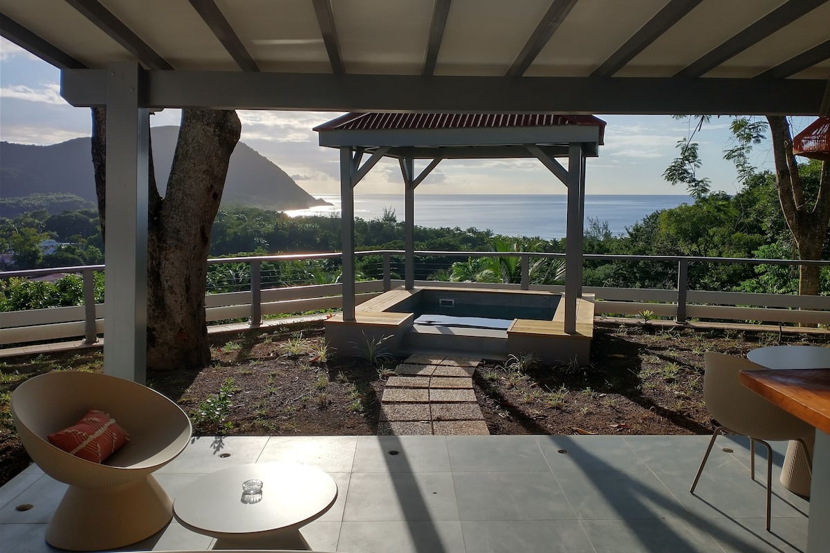 A covered outdoor area with a pool, seating, and a view of the ocean.
