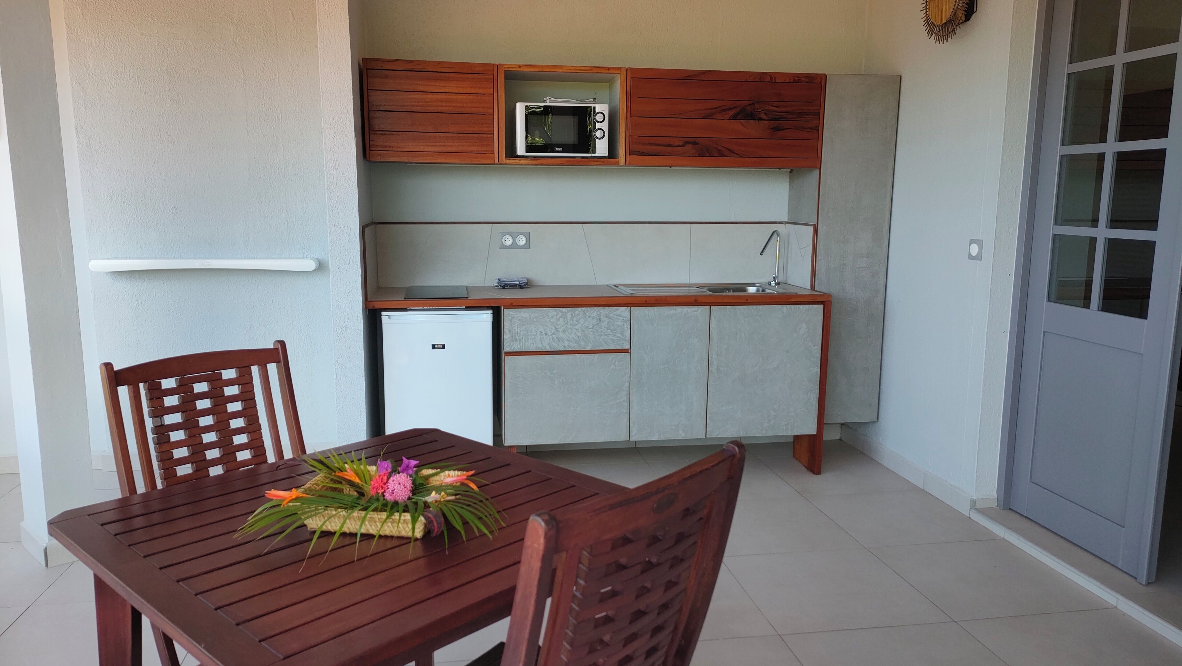 Una kitchenette compacta con microondas, un refrigerador pequeño y armarios de madera.