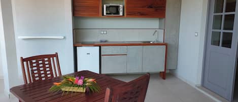 Uma cozinha compacta equipada com micro-ondas, um refrigerador pequeno e armários de madeira.