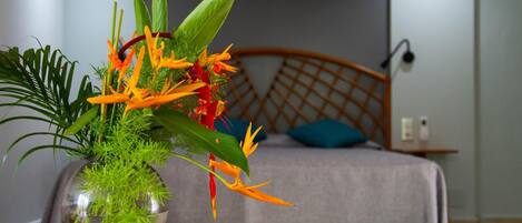 A bed with a wooden headboard, a bedside table, and a vase with a plant.