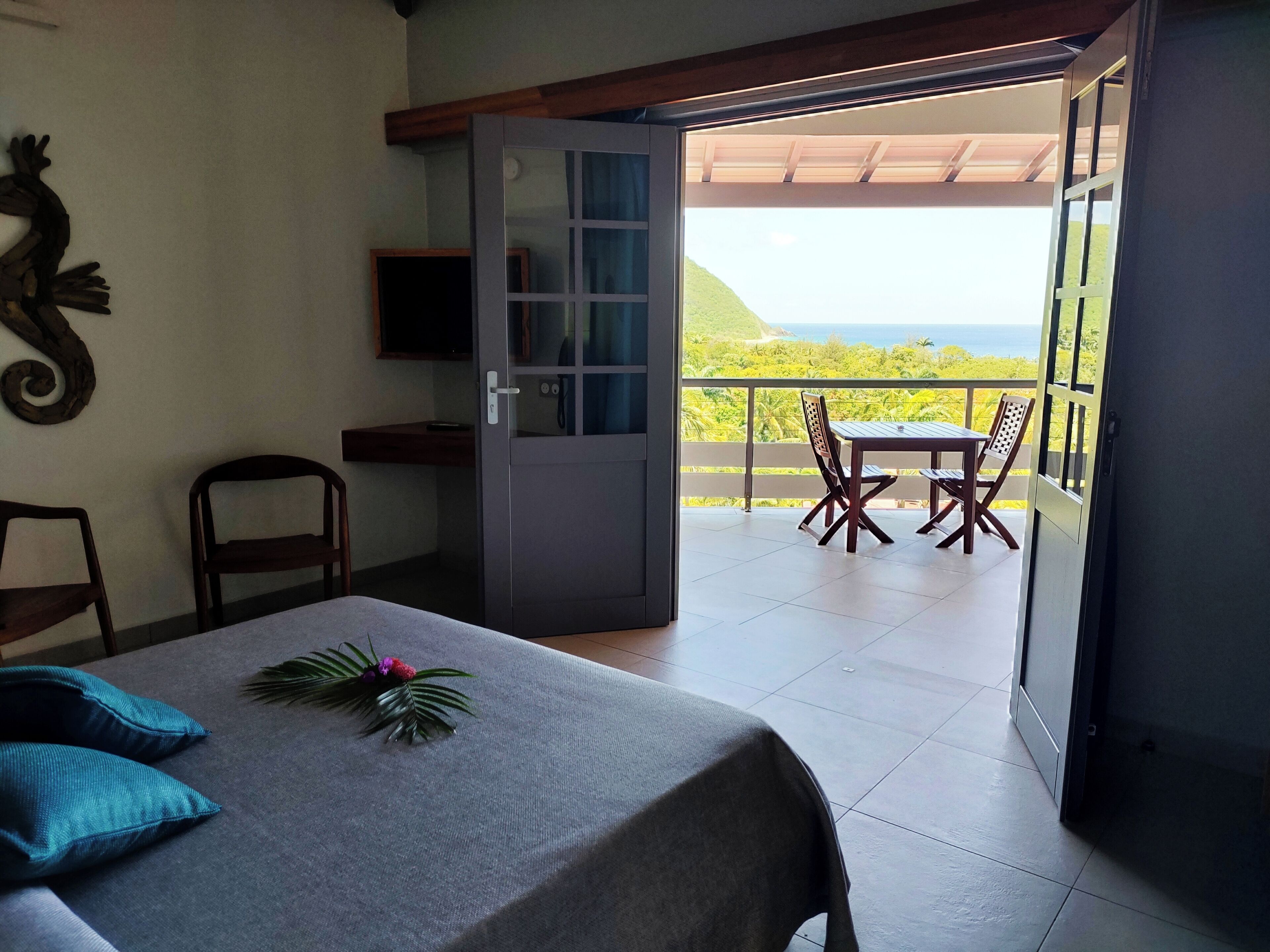 Una habitación con cama, una mesa con mantel, una silla y un balcón con mesa y sillas.