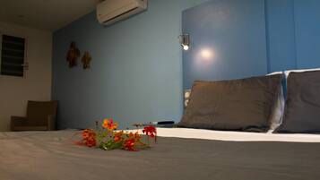 A bedroom with a bed, a nightstand, a wall-mounted air conditioner, and a wall-mounted lamp.
