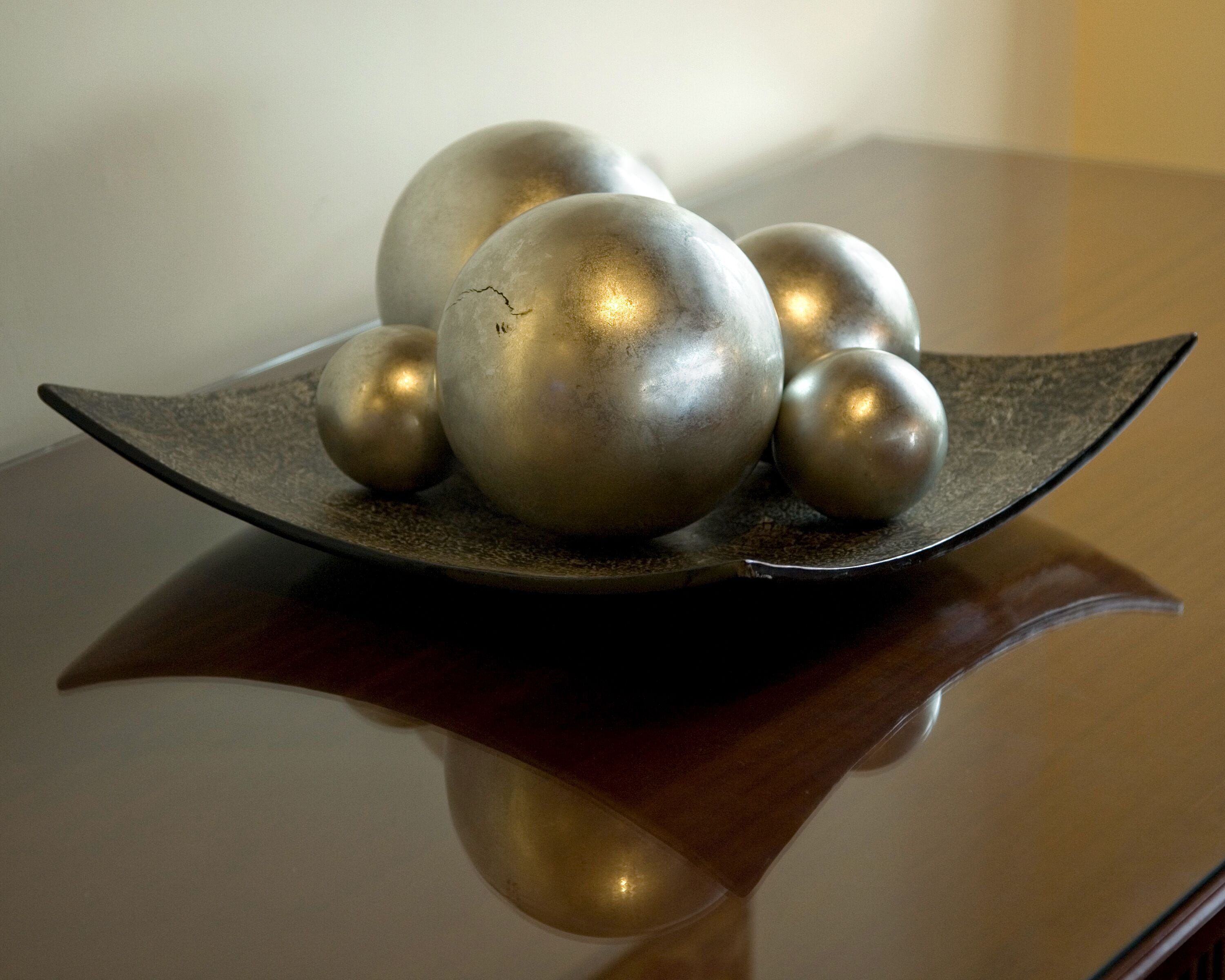 Une surface réfléchissante avec un objet sphérique métallique et une plaque incurvée.