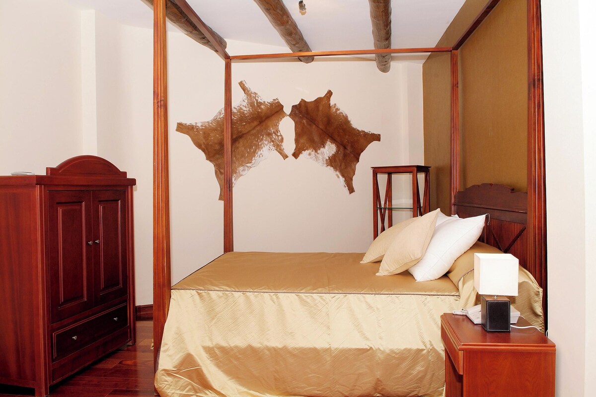 A room with a bed, wooden furniture, and a unique wall decoration.