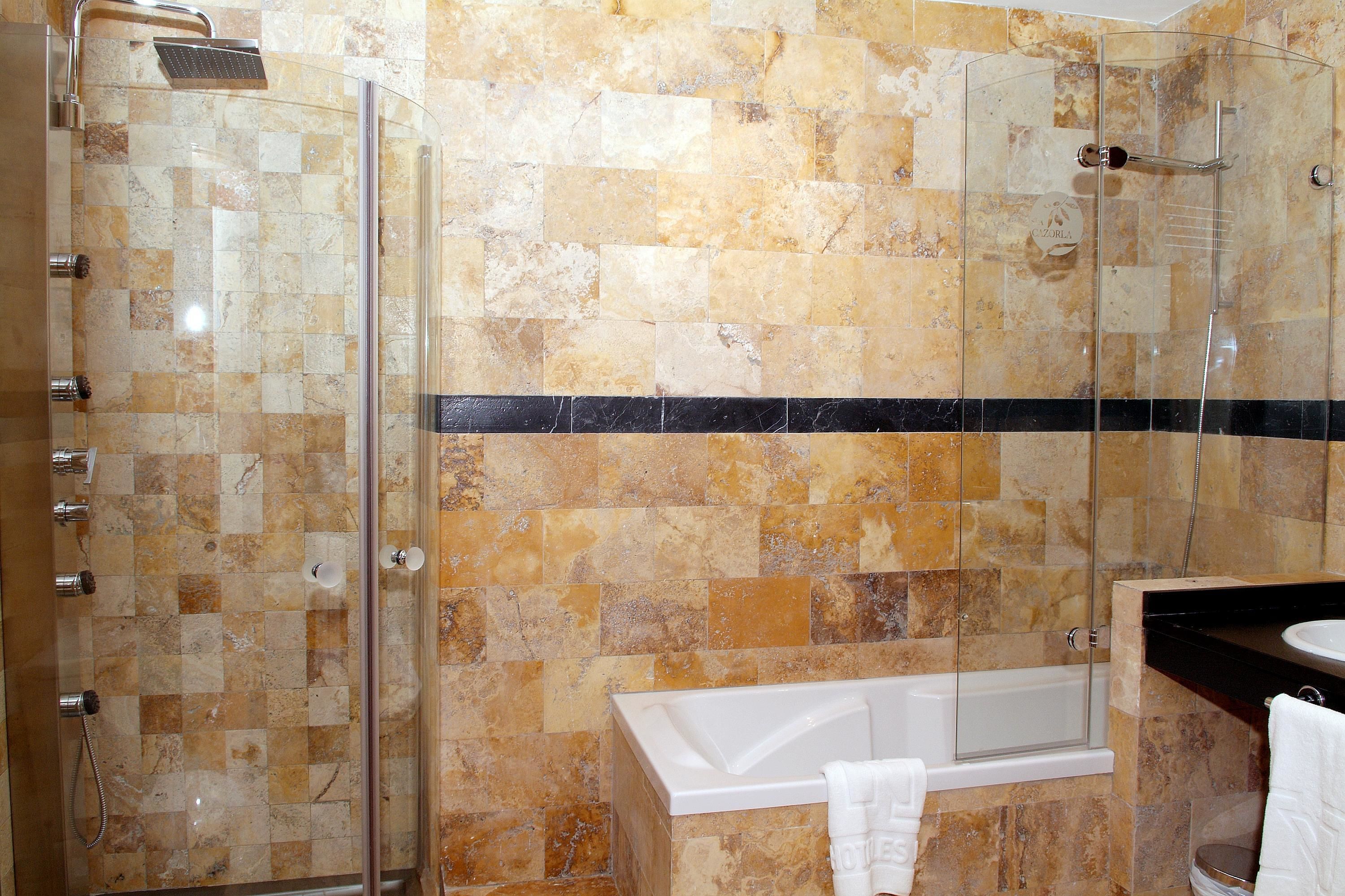 Un baño con ducha de vidrio, bañera y lavamanos.
