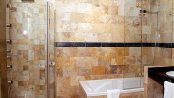 Un baño con ducha de vidrio, bañera y lavamanos.