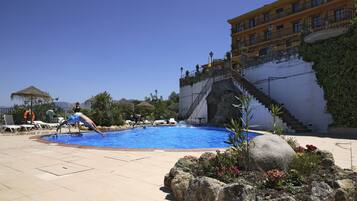 Een buitenzwembad, ligstoelen bij het zwembad