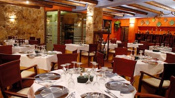A restaurant with multiple tables set for dining, featuring white tablecloths and silverware.