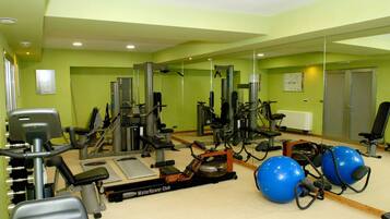 Une salle de sport équipée de divers appareils d’exercice, notamment des tapis de course, des appareils de musculation et des ballons d’exercice.