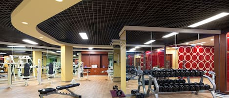 Ett gym med olika typer av träningsutrustning, inklusive hantlar och styrketräningsmaskiner.