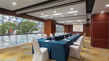 A conference room with a long table, white chairs, and a banner with a logo.