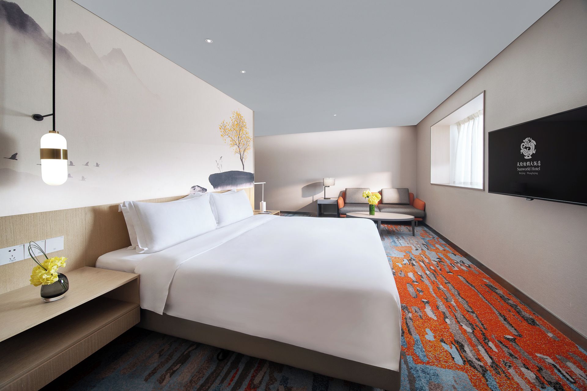 Habitación de hotel con cama, mesita de noche, lámpara y televisor montado en la pared.