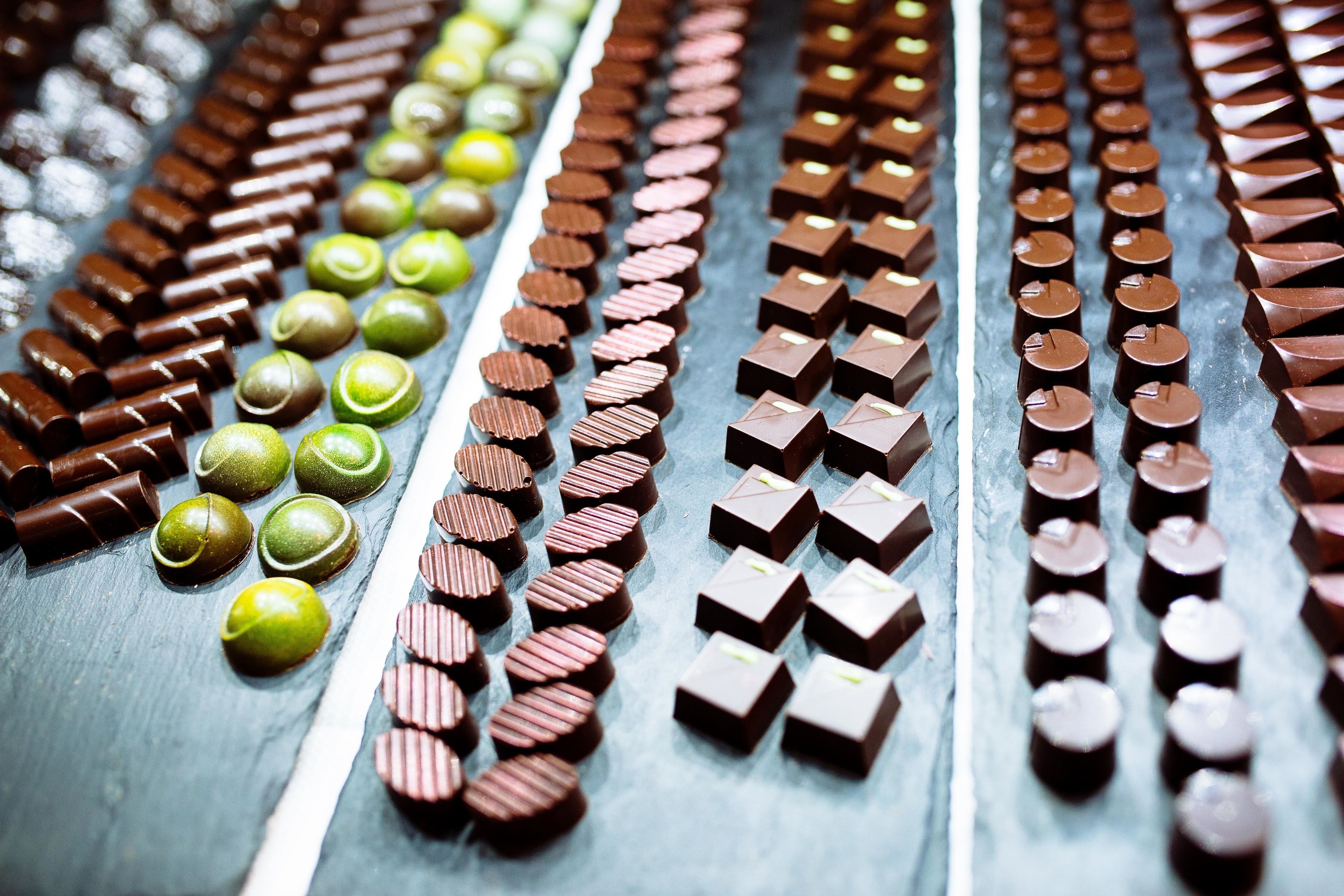 Une variété de chocolats disposés en rangées sur une surface.