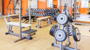 Una palestra con attrezzatura per sollevamento pesi, panche e uno specchio a parete.