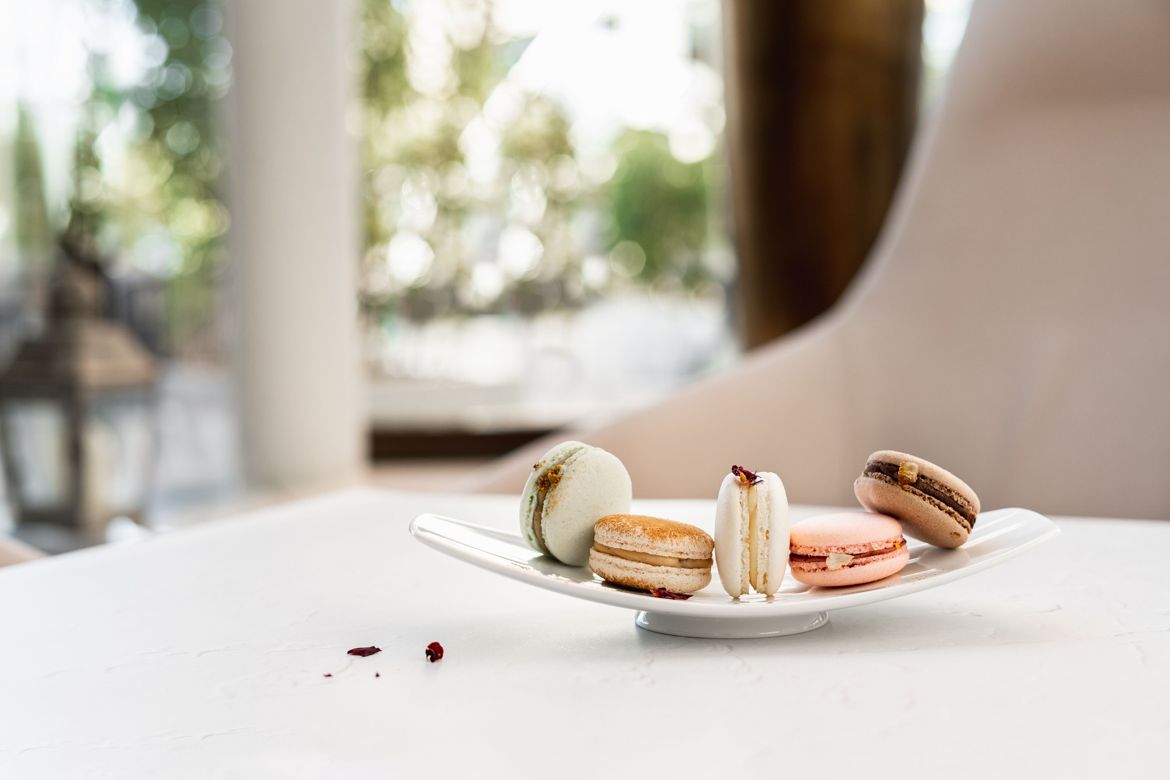 Un piatto bianco con tre macarons su una superficie bianca.