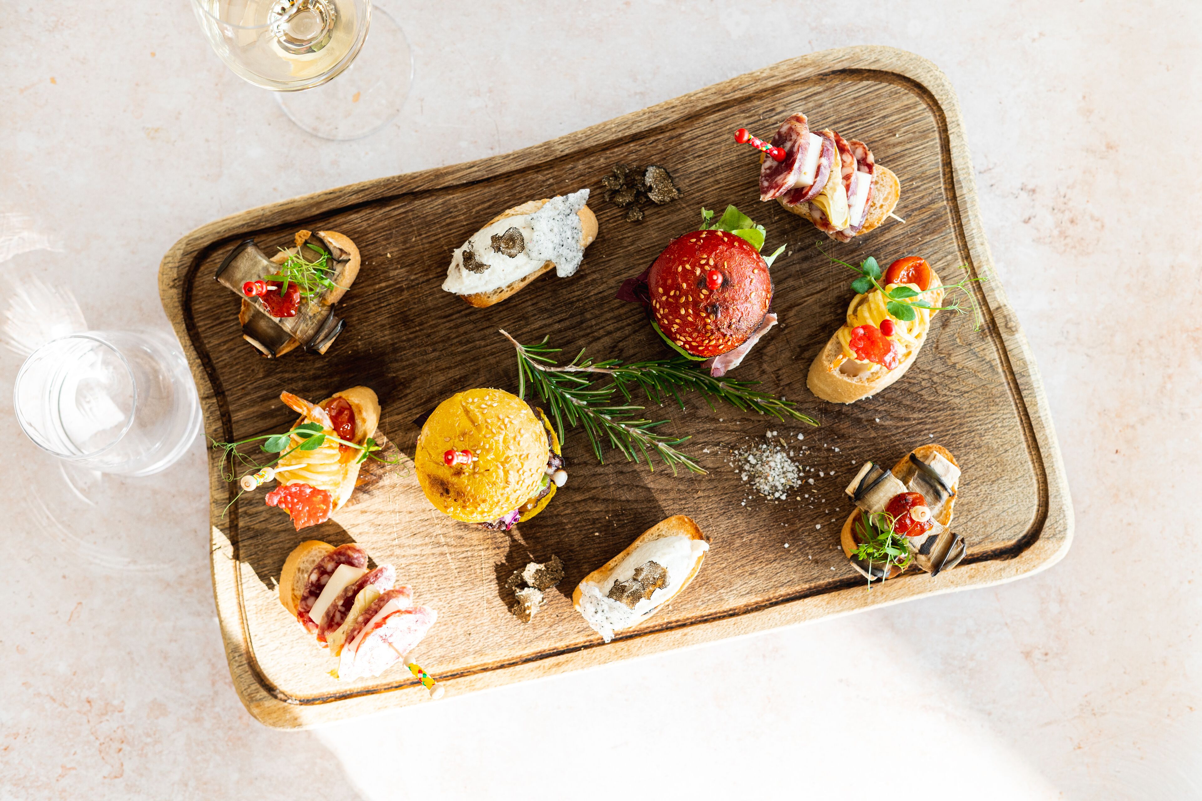 A wooden board with various food items and a glass of wine.