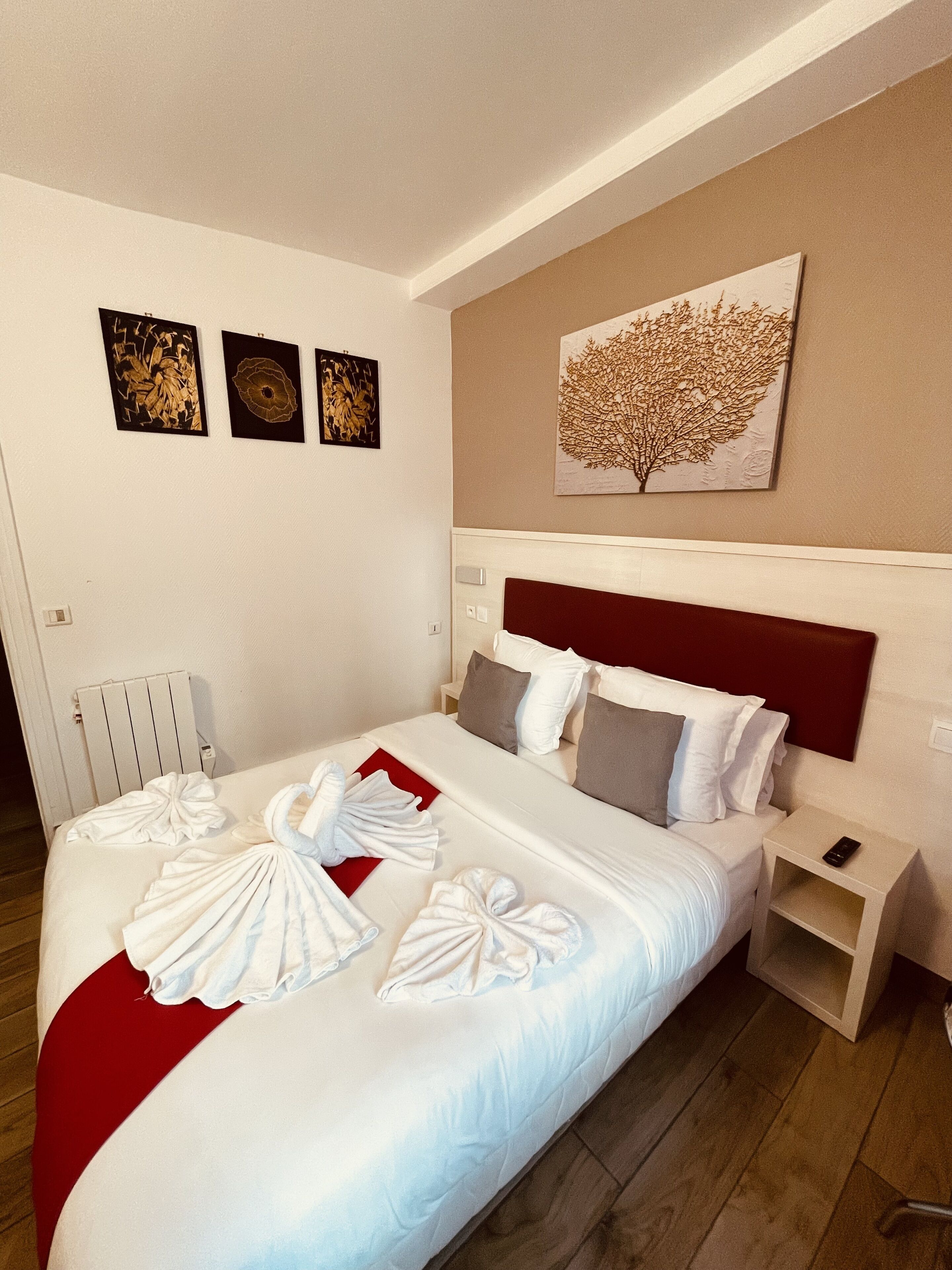Una habitació d'hotel amb un llit gran, un panell frontal vermell i tres quadres penjats a la paret.