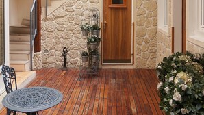 A wooden deck with a metal railing, a door with a stone wall, and a staircase. - Hôtel Istria by Magna Arbor (Paris)