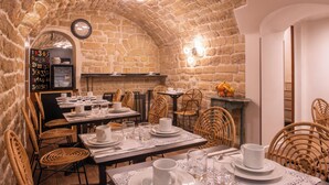 A restaurant with stone walls, wicker chairs, and tables set for dining. - Hôtel Istria by Magna Arbor (Paris)