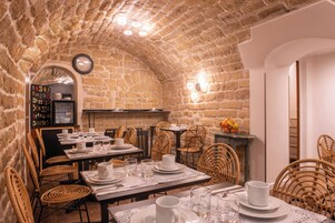Un ristorante con pareti in pietra, sedie in vimini e tavoli apparecchiati per la cena.