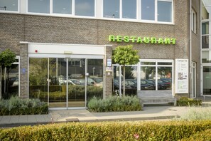 Ein Restaurant mit Glastür, einem Schild darüber und einem Parkplatzschild zur rechten Seite.