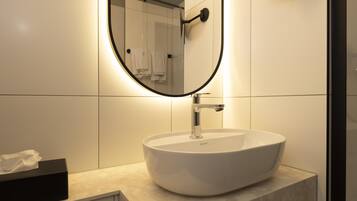 A modern bathroom with a round mirror, a white sink, and a towel rack.