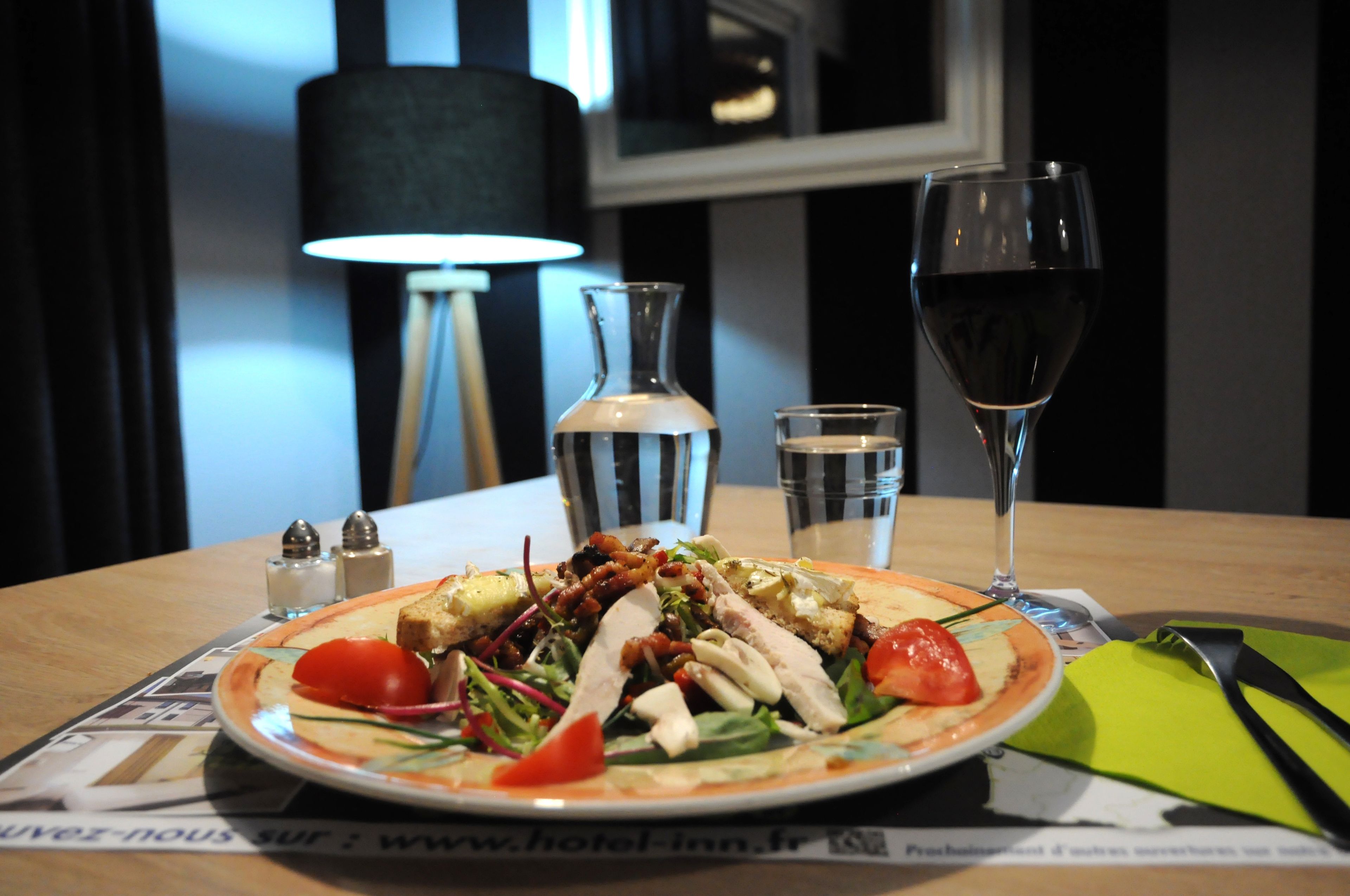 A dining table with a plate of food, two glasses of water, and a wine glass.