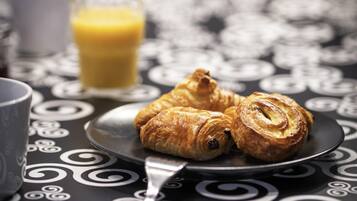 A plate with croissants and a glass of orange juice on a table with a black and white pattern.