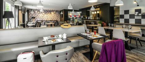 A modern restaurant with a bar area, seating, and a visible kitchen.