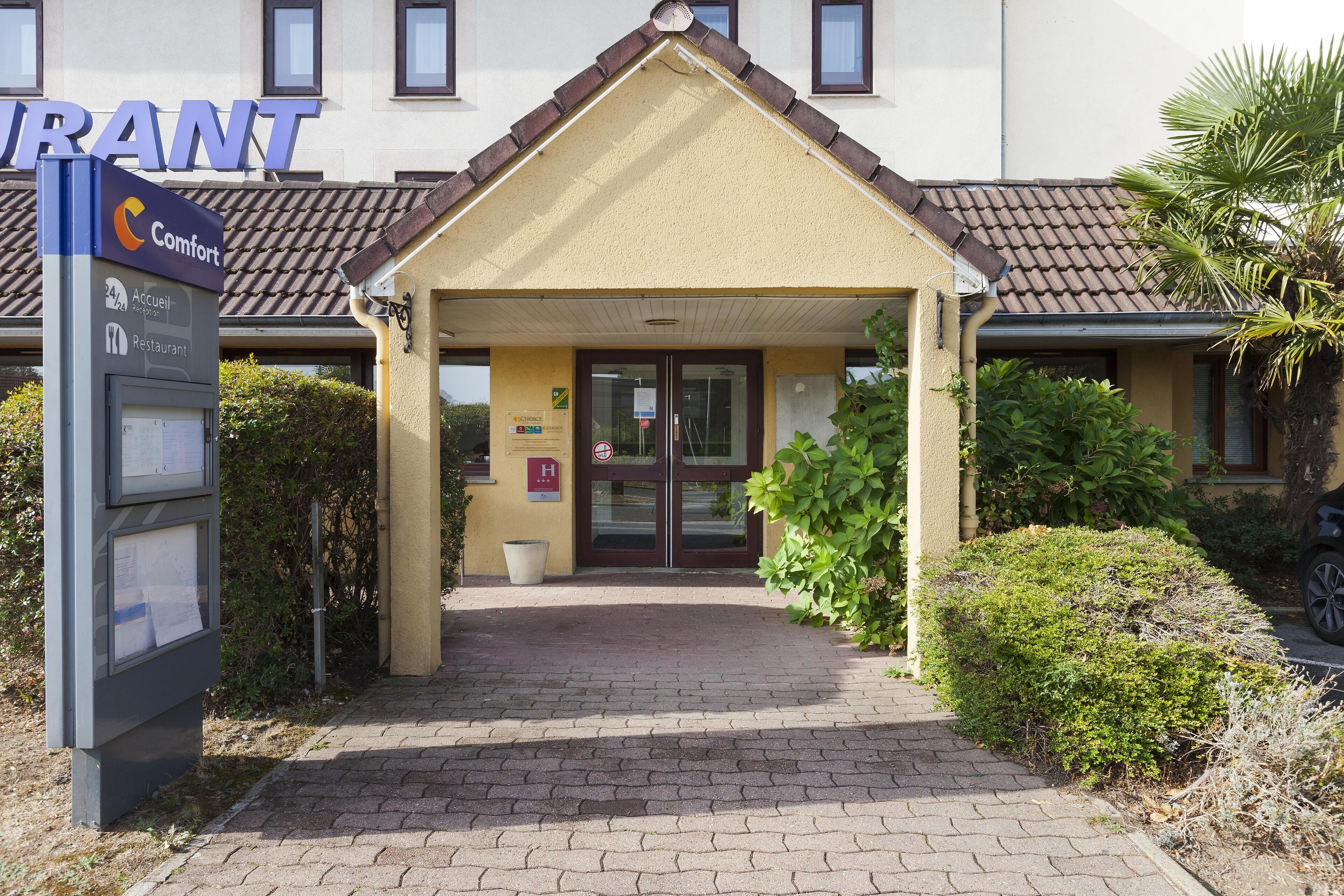A hotel entrance with a sign for 'Comfort' and a reception desk.