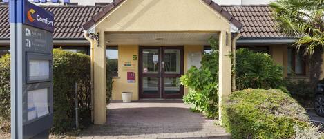 A hotel entrance with a sign for 'Comfort' and a reception desk.
