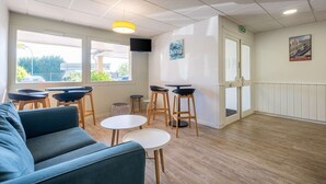 A modern interior with a sofa, round tables, and bar stools. - Comfort Hotel Linas Montlhery (Linas)