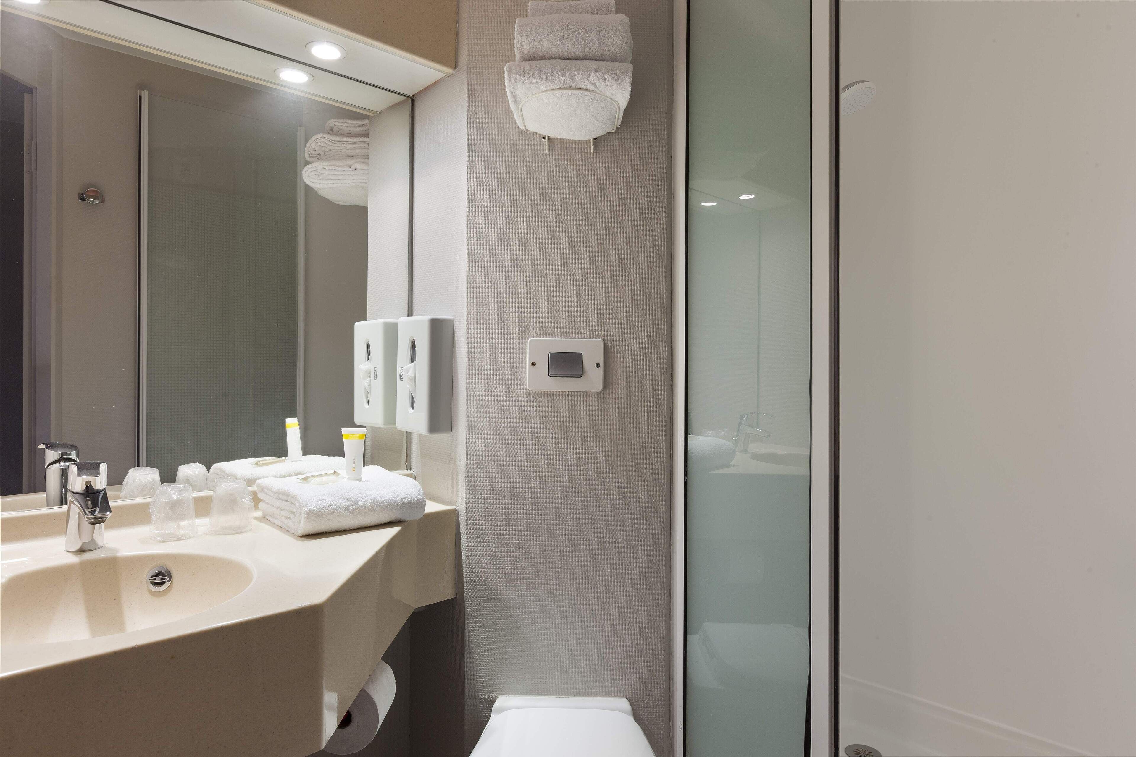 Une salle de bain moderne avec un lavabo, un miroir et une douche à parois en verre.