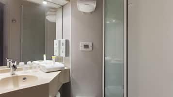 A modern bathroom with a sink, mirror, and glass shower enclosure.
