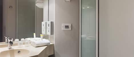 Une salle de bain moderne avec un lavabo, un miroir et une douche à parois en verre.