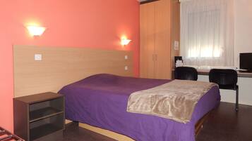 A hotel room with a bed, a desk, and a chair.