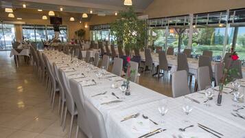 Un restaurante con mesas largas dispuestas para comer, sillas y plantas en macetas.