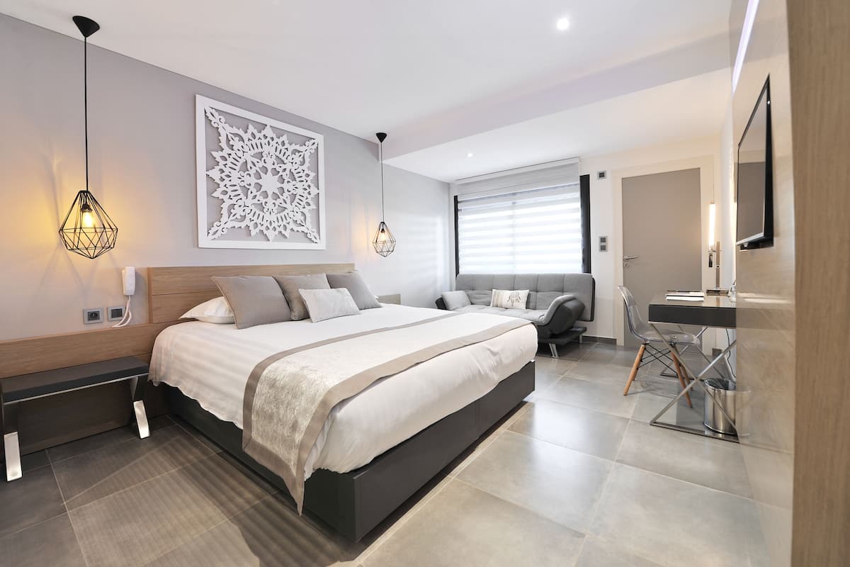 A modern bedroom with a large bed, bedside tables, a desk, and a chair.