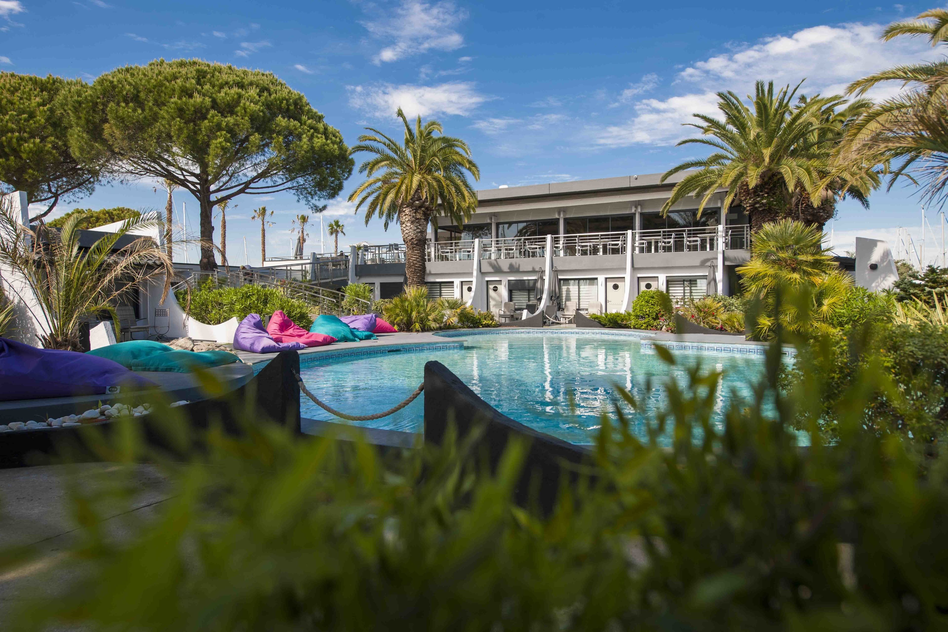 Un área de piscina con sillones reclinables y un edificio con balcones.
