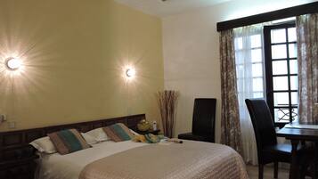 A bedroom with a bed, bedside table, lamp, chair, and a window with curtains.