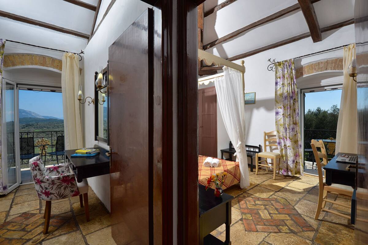 A room with a bed, a desk, a chair, and a balcony with a view.