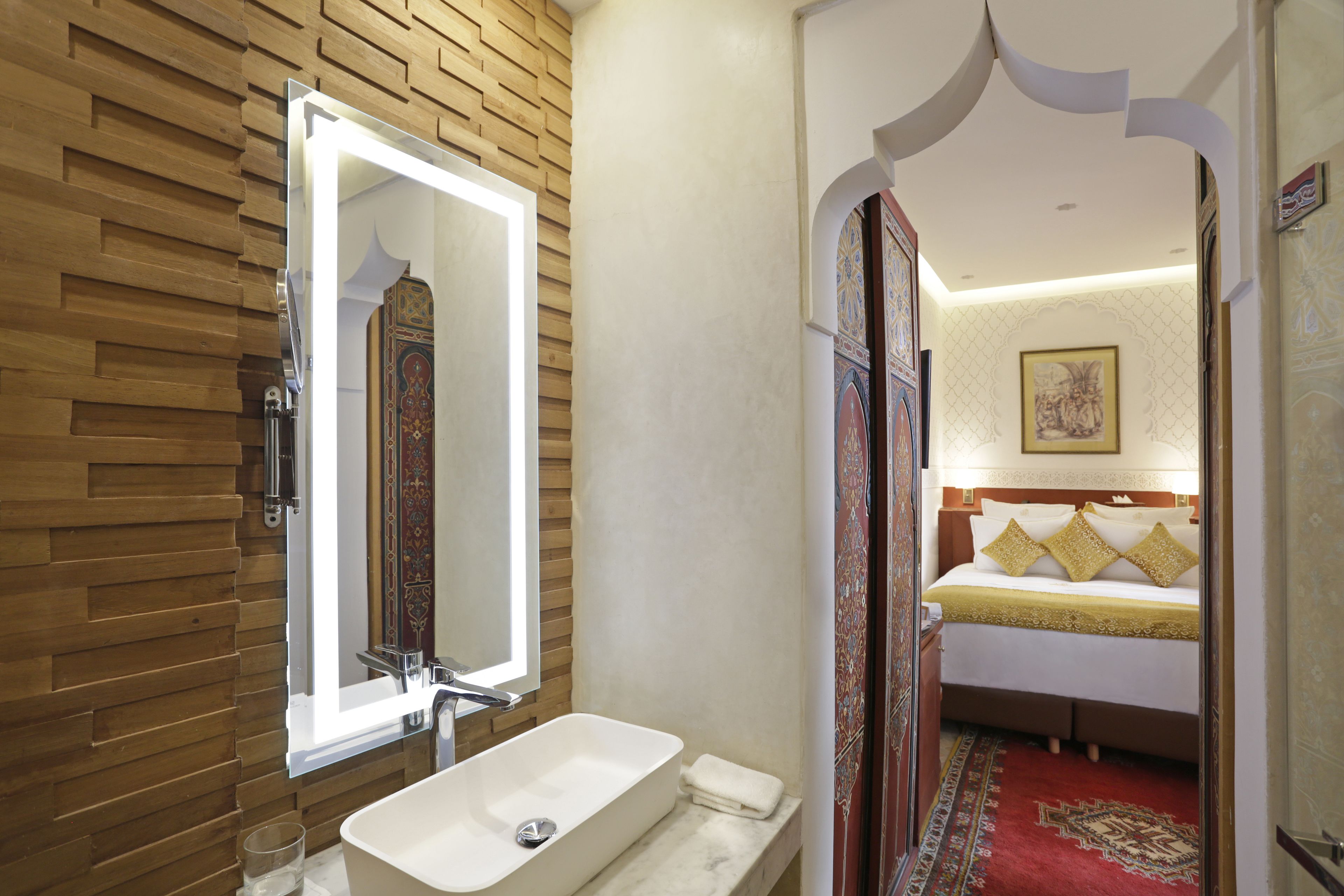 A bathroom with a wooden wall, a white sink, and a mirror.