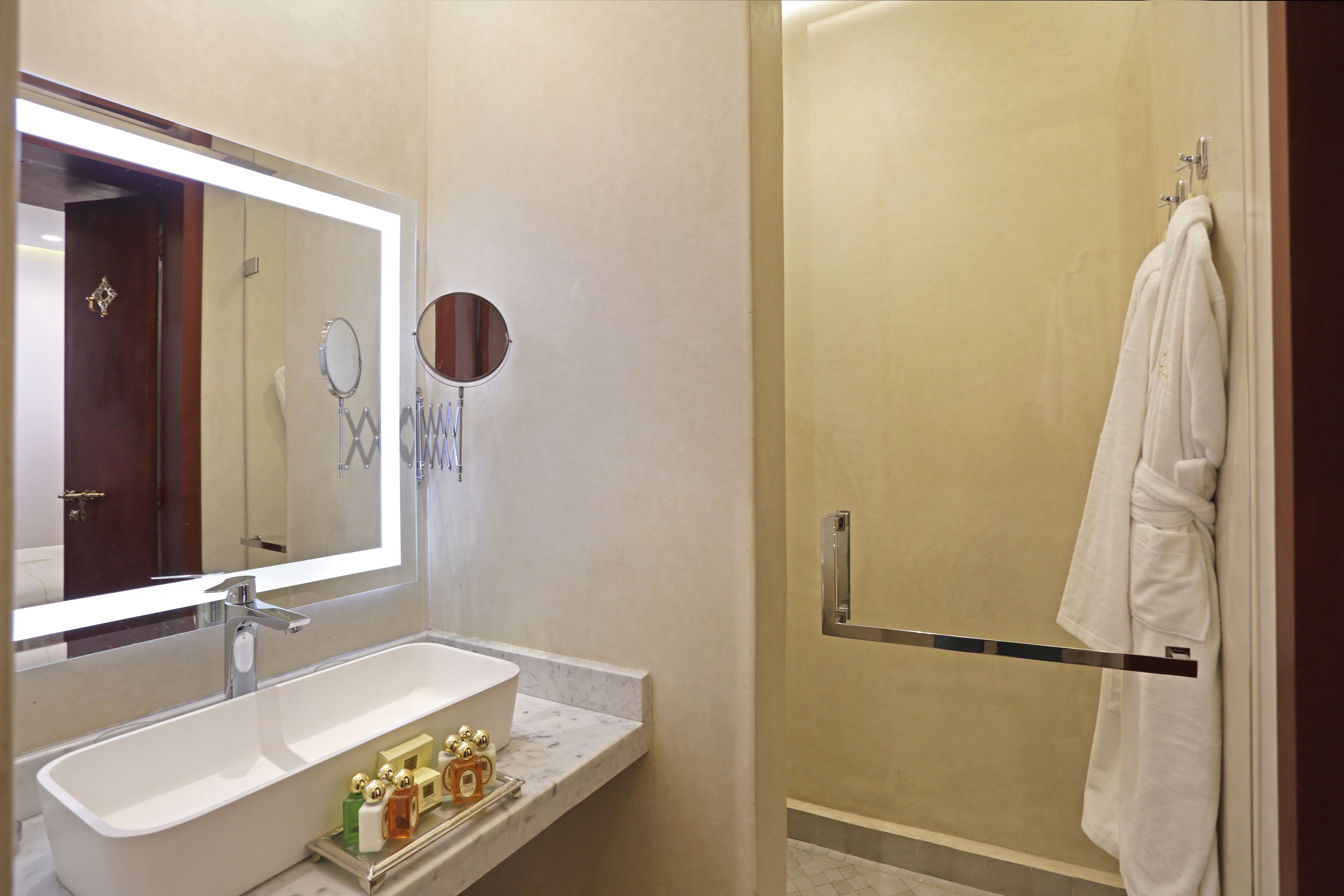 A bathroom with a large mirror, a sink, and a towel rack.