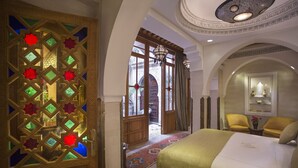 A hotel room with a large bed, a decorative door, and a view of the courtyard. - La Maison Arabe Hotel, Spa and Cooking Workshops (Marrakech)