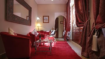 Een kamer met rode meubels, een spiegel, een lamp en een rood tapijt.