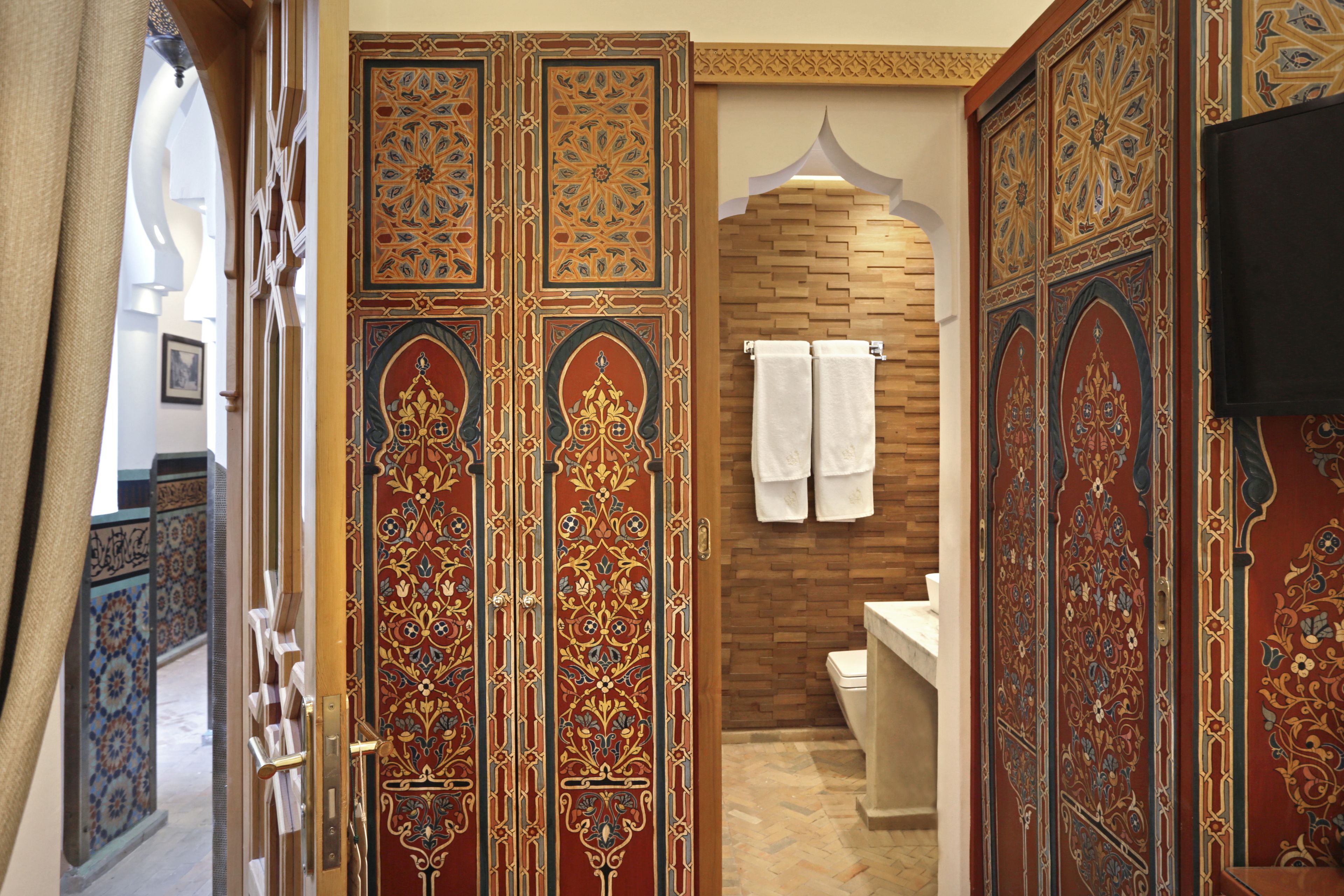 An ornate bathroom with intricate tile work, a wooden wall, and a modern sink.