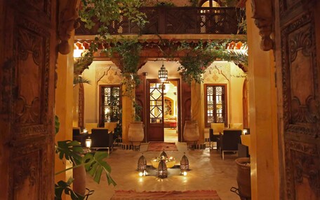 An ornate lobby with a central chandelier, seating areas, and a decorative archway.